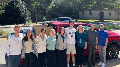 People in Duke attire stand in front of a pickup truck full of supplies.