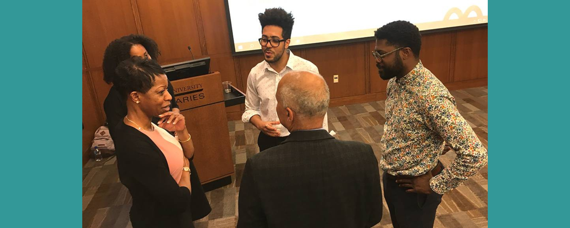 Several people standing in a group taking to each other.