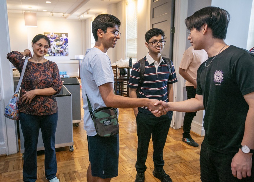 International students shaking hands in a group in a museum.