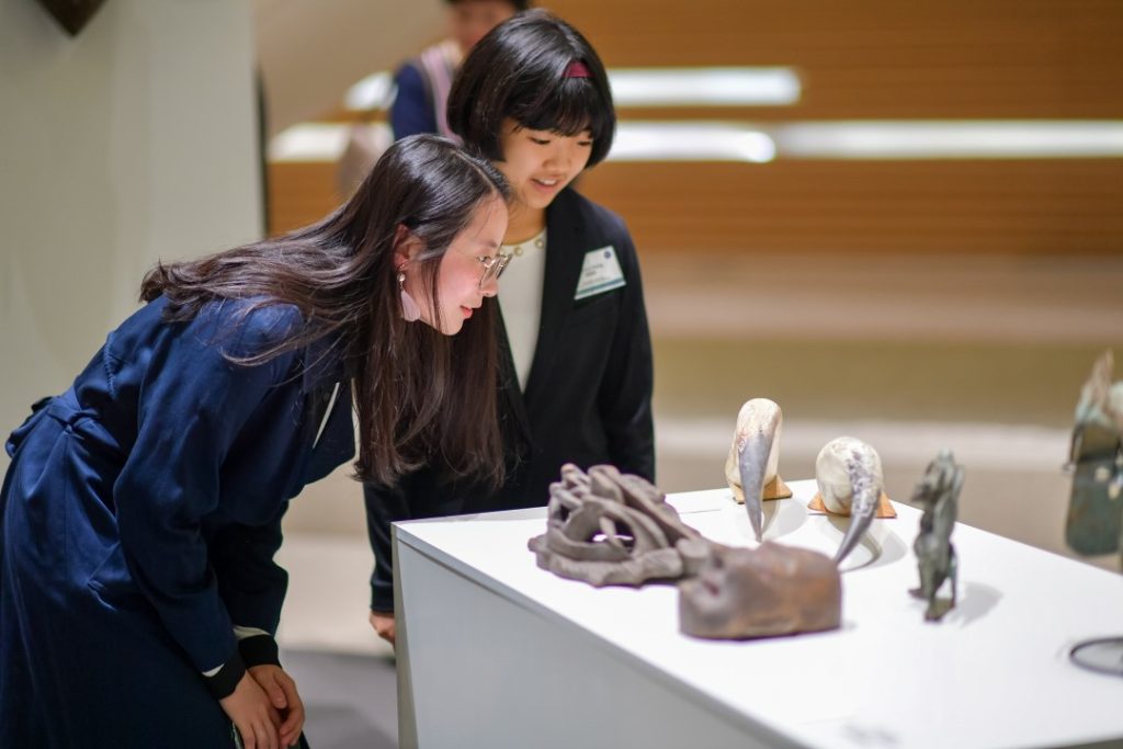 Two DKU students looking at pieces on a table in a museum.